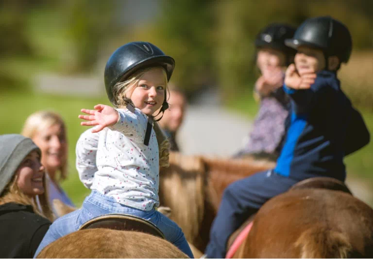 machające ręką dzieci na koniach